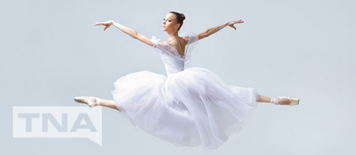 Ballerina leaping through the air in white tutu
